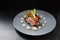 Menu main course with roasted veal, morels and vegetables on a blue gray plate on a dark table, copy space