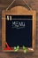 Menu written with chalk on aged blackboard with chili peppers and parsley hanging on wooden wall