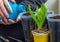 Menâ€™s hands pour water from a plastic bottle into a container with soil for growing plants. Plastic pot for seedlings with earth