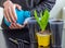 Menâ€™s hands pour water from a plastic bottle into a container with soil for growing plants. Plastic pot for seedlings with earth