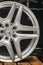 Mercedes Benz logo aluminum cast wheel, close-up, original silver wheel new in black background vertical concept