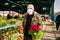 Merchandiser in medical mask and gloves is selling potted flowers