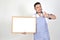 Merchant Asian man in white and blue apron to holding blank white broad for put some text or wording for present advertising