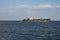 Merchant ship sails on a blue sea in clear weather.