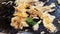 The merchant in street food market are making fried mussels in frying pan for customers.