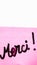 Merci handwriting text close up isolated on pink paper with copy space. Writing text on memo post reminder