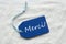 Merci Mean Thank You On Blue Label Sand Background