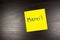 Merci\' written on a yellow sticky note (thank you in French) on black background