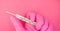 Mercury thermometer in hand of paramedic. Hand in pink glove holds thermometer on pink background with copy space. Health care