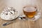 Meringue with chocolate in saucer, cup of tea and spoon