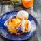 Meringue with ice cream of sea buckthorn on a blue plate on a dark wooden background