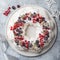 Meringue pavlova wreath cakes with whipped cream and frozen berries