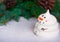 a meringue snowman stands in the snow in the background a Christmas tree branch