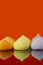 Meringues, various colours, reflected on an orange background.