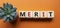 Merit symbol. Concept word Merit on wooden cubes. Beautiful orange background with succulent plant. Business and Merit concept.