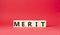 Merit symbol. Concept word Merit on wooden cubes. Beautiful red background. Business and Merit concept. Copy space