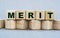 MERIT - word on wooden cubes on a beautiful gray background