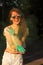 Merry brunette girl in sunglasses playing with green Holi powder