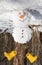 Merry cheerful cute snowman in yellow boots upside down stands in a snowy forest, upside down funny photo