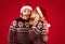 Merry Christmas. Beautiful woman in Santa hat kissing her boyfriend over red background