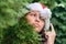 Merry Christmas concept. Portrait of woman points by finger to the pompom of santa claus red hat through green fir tree branches