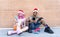 Merry christmas! happy diverse couple of friends wearing xmas santa hat interacting with smartphone sitting against background