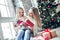 Merry Christmas and Happy Holidays! Cheerful mom and her cute daughter girl exchanging gifts