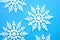 Merry christmas and happy holidays concept with close up on a bunch of white snowflakes isolated on minimalist blue background