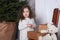 Merry Christmas and happy holidays! New Year 2020. little curly girl stands next to gifts on chair. child receives a Christmas pre