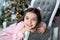 Merry Christmas, happy holidays! New Year. girl with bows on her head against background of Christmas tree lies on sofa and dreams