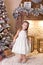 Merry Christmas, happy holidays! New Year. little girl is standing in a dress in bright New Year`s interior. little child decorate