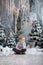 Merry Christmas and Happy New Year! Charming little boy is sitting at home, snowy winter decorated tree on background. New Year an