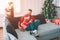 Merry Christmas and Happy New Year. Family picture. Young man sits on sofa with daughter. They spend time tgether. Woman