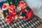 Merry Christmas and Happy New Year. Kid sits between parents and open gift. She is concentrated. Guy holds red lantern