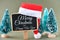 Merry Christmas and Happy New Year text on a small chalk board surrounded by Christmas trees. High resolution photography as a Chr