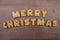 Merry Christmas message composed with biscuit letters over a wooden board