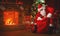 Merry Christmas! santa claus near the fireplace and tree with gi