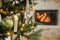 Merry Christmas! Stylish christmas bauble and candle on tree close up against burning fireplace. Beautiful decorated christmas