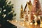 Merry Christmas. Stylish christmas wooden house, glitter christmas tree and golden reindeer in festive lights. Miniature fairy