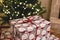 Merry Christmas! Stylish wrapped christmas gifts on arm chair against christmas tree with festive lights. Atmospheric Christmas