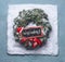 Merry Christmas text lettering. Wreath with green fir branches and red framed sign and Santa hat in snow on blue background, top v