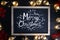 Merry Christmas Typography on Blackboard Between Light Bulbs and