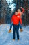 Merry couple having fun in the winter forest in red sweatshirts