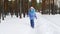 A merry girl runs along the path in a snow-covered forest