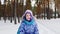 A merry girl runs along the path in a snow-covered forest