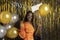 Merry glad pleased young multiracial woman in orange gala dress with festive gold and silver balloons against lametta