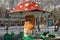 Merry-go-round in the form of mushroom of the old grandfather in the Park of attractions covered with snow