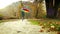 Merry little boy jumping in a park with multi-coloured umbrella