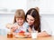 Merry little girl and her mother having breakfast