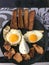 A merry smiling face, a face made of food, with eyes of fried eggs with yolks, a mouth of meat, nuggets. Creative breakfast